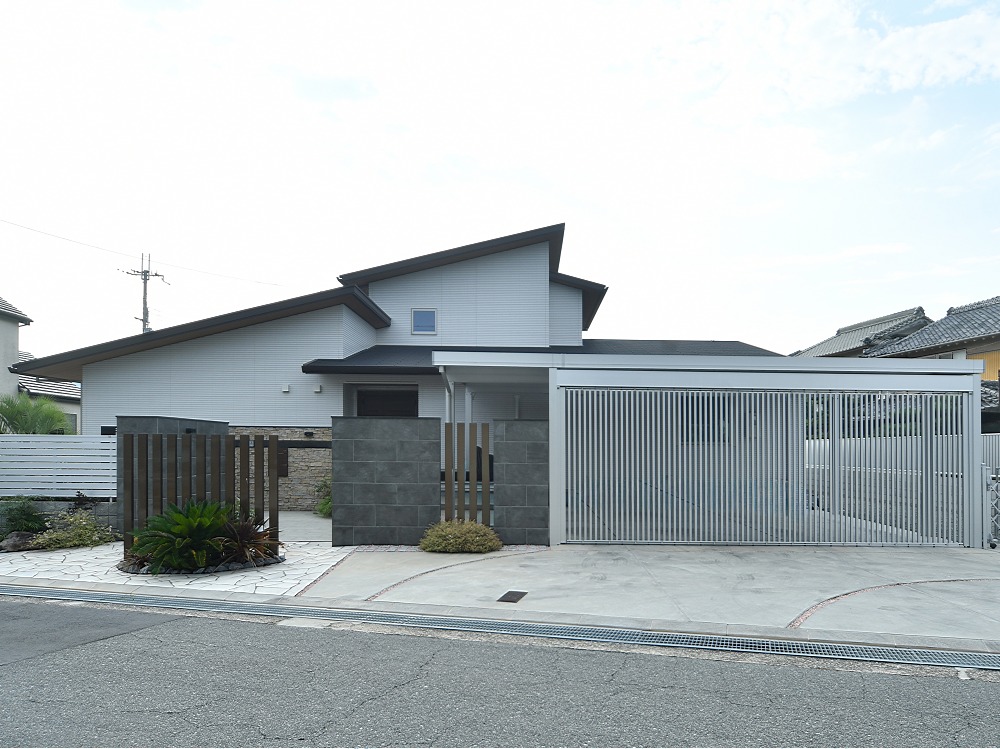【姫路市　H様邸】広いエントランスを活かした、存在感のあるクローズ外構のデザインが実現しました。重厚感のある素材選びと洗練されたラインが、居住空間を引き立てています。アクセントとして配置した植栽が、エクステリアに生き生きとした表情を添えています。また、視界を適度に遮ることでプライバシーを確保しつつ、開放感も失わない構造になっています。 おしゃれでありながら安心感のある空間を楽しんでいただけます。駐車スペースには横にスライド開閉できる縦格子のスライドゲートを採用し、お車の出し入れもスムーズです。